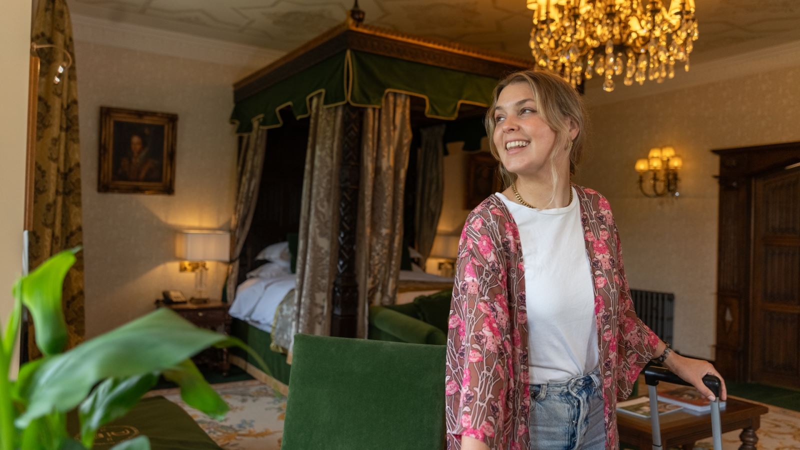 A photo of a smiling woman holding a case in a bed chamber at Thornbury Castle, Bristol, UK